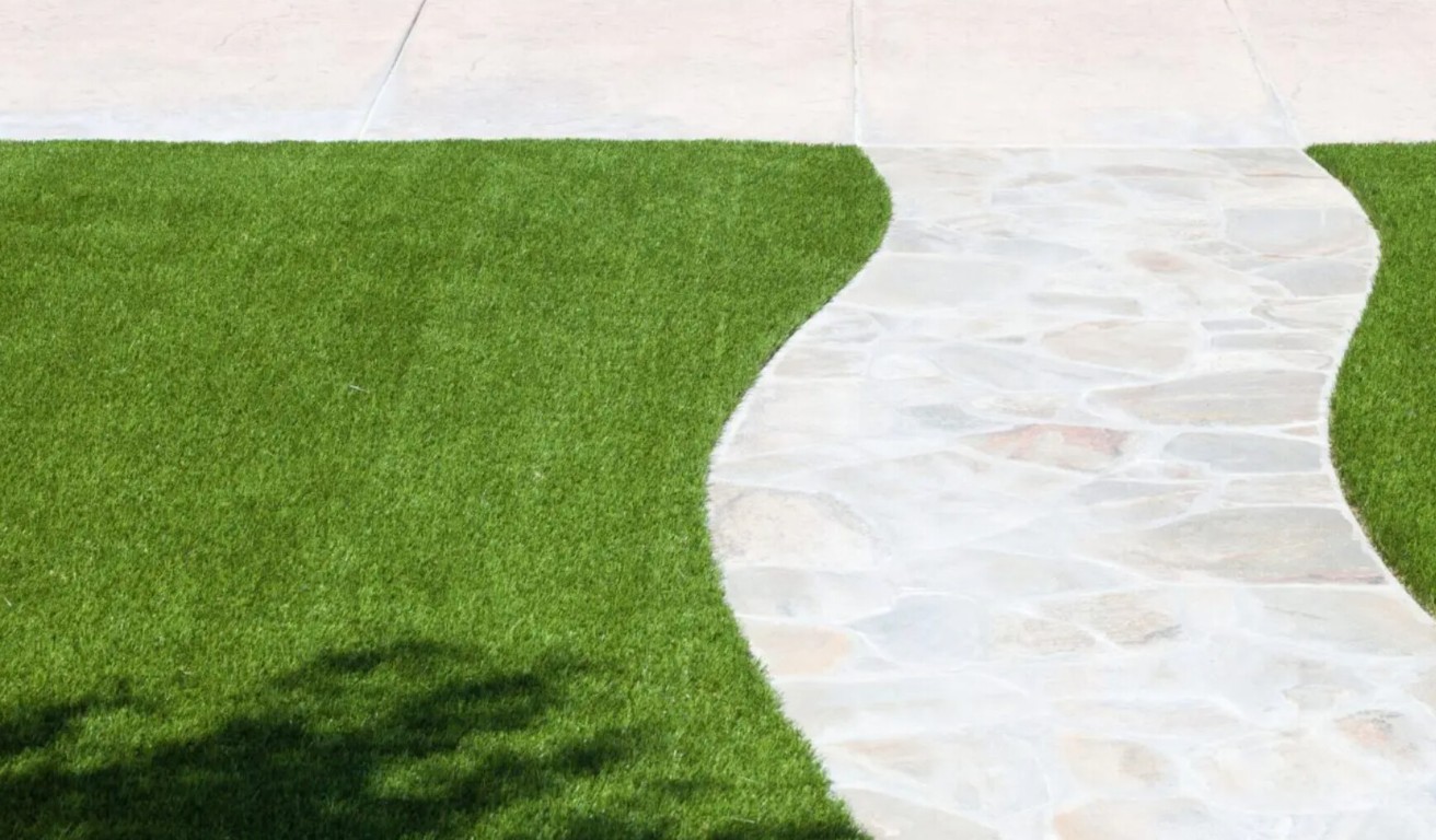 Professional artificial grass installation along curved pathway with pavers in Moreno Valley, CA